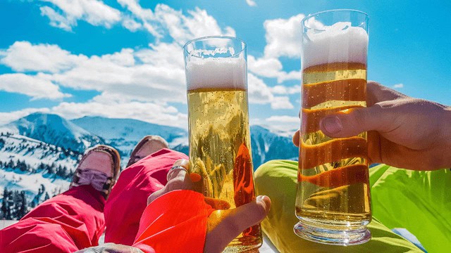 Clinking beer glasses with snowy mountain background