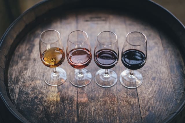 Four glasses of different wine on top of a wine barrel