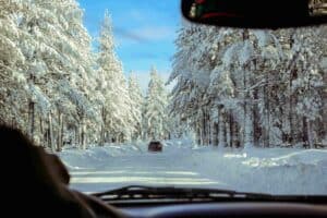 view through windshield of car on snowy mountain road.