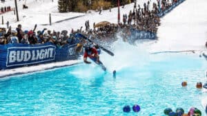 Skier attempts to ski over a pool of water with onlookers cheering them on