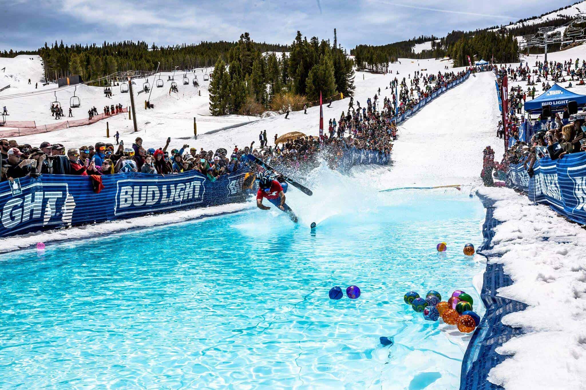 Skier attempts to ski over a pool of water with onlookers cheering them on