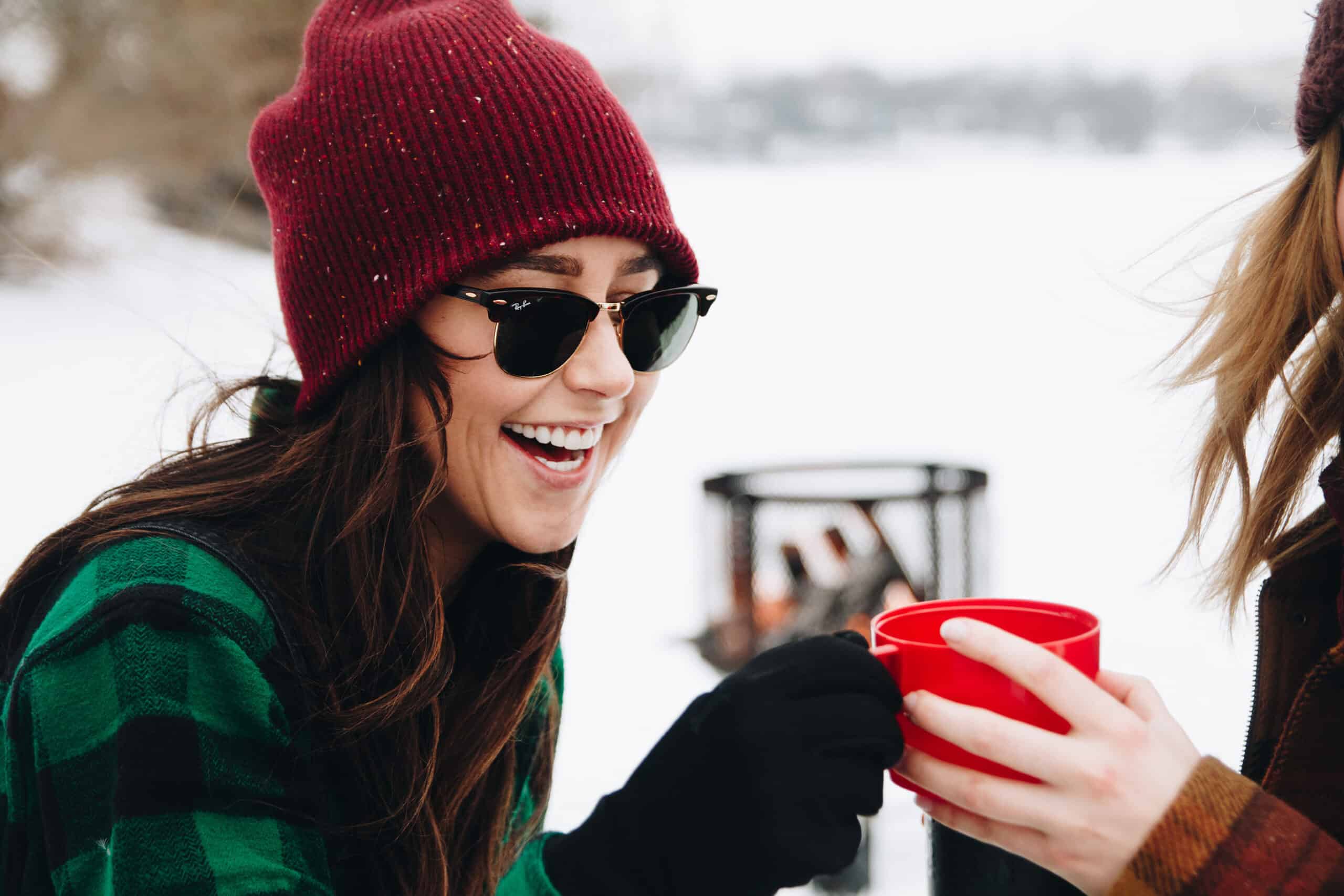 woman smiling wearing winter clothes and shades