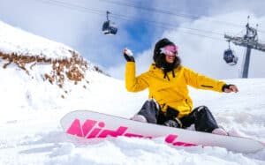 woman throwing a snowball while snowboarding