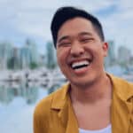 Man smiling in front of city skyline and waterfront